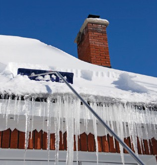 snow beging removed from a roof with a rake