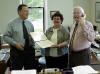 Three people standing by a desk - thumbnail link to larger photo